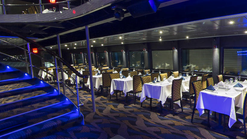 Luxury yacht dining area with staircase and formal table settings.